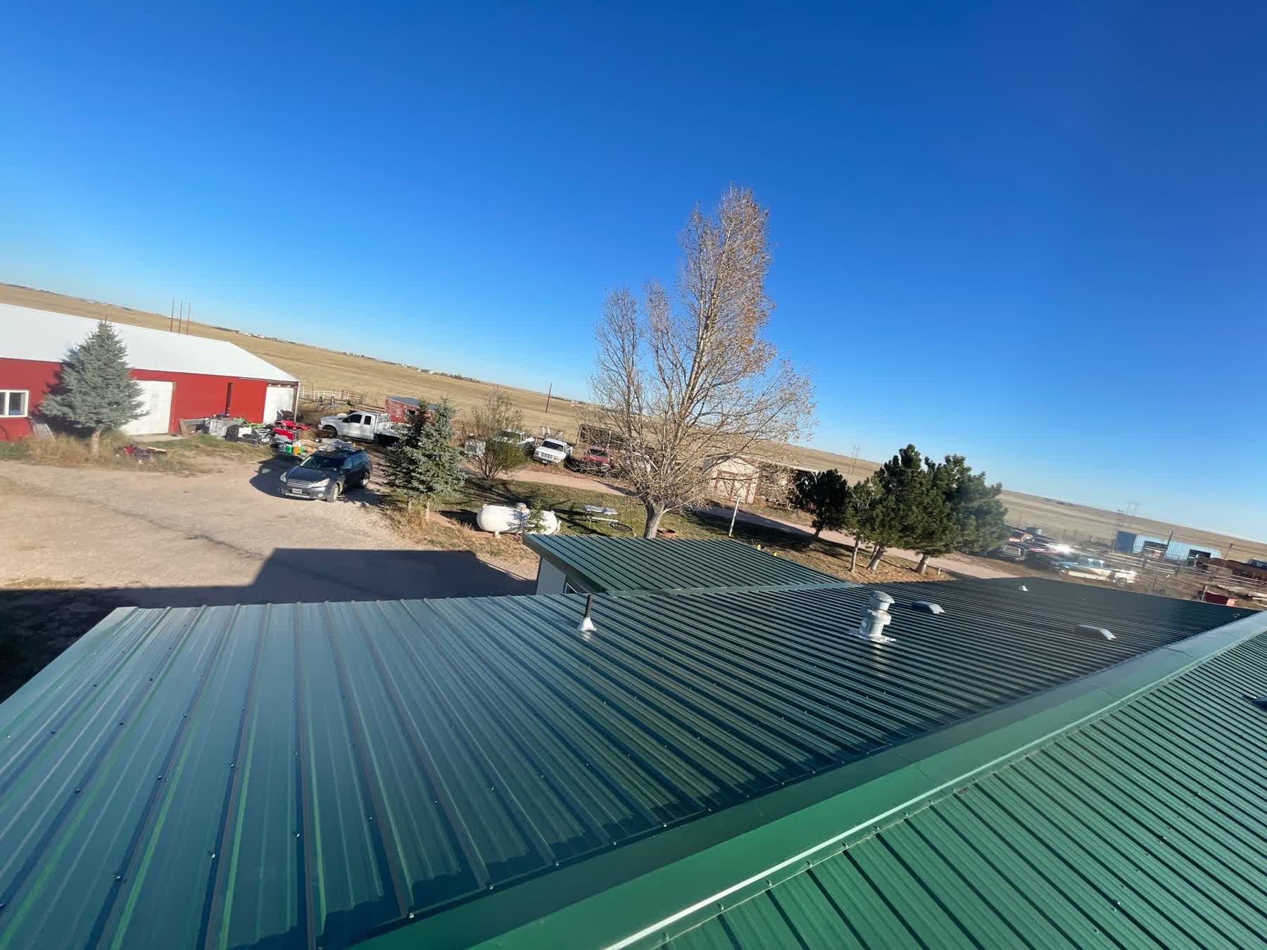 Finished metal roof overlooking a rural yard and neighboring structures